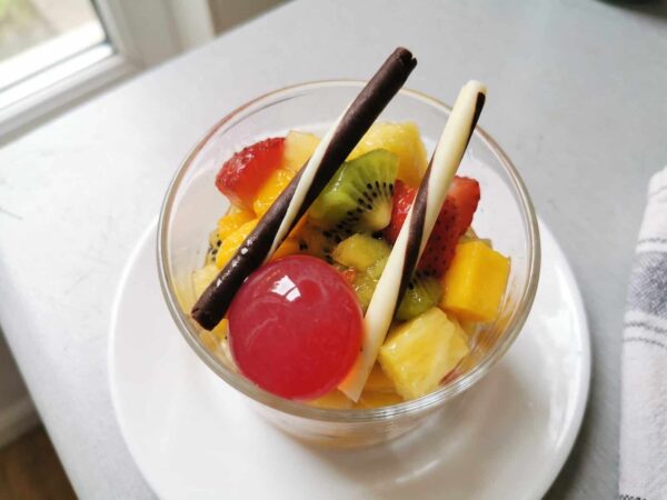 Verrine de salade de fruits (kiwi, fraise, mangue, ananas), deux cigarettes en chocolat et une Pearl de Framboise