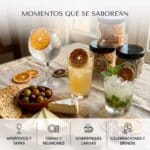 Mesa de aperitivo con cócteles decorados con rodajas de cítricos deshidratados y tarros abiertos