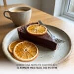 Porción de tarta de chocolate con rodajas de naranja deshidratada encima, junto a un café