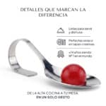 Cucharilla de acero con una única esferificación de frambuesa sobre fondo neutro