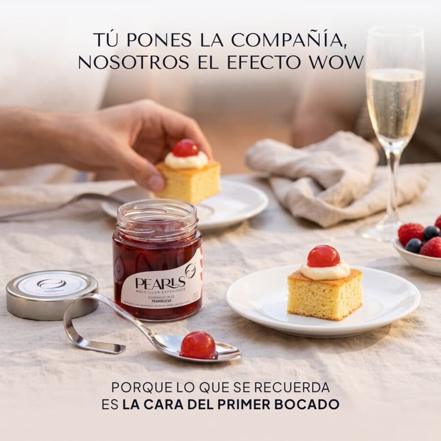 Frasco de Pearls de frambuesa en primer plano sobre una mesa puesta con copas y tapas dulces