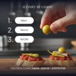 Mano colocando una perla de oliva verde Pearls sobre una tosta de tomate y anchoa