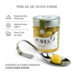 Frasco de Pearls de oliva verde con la cucharilla de servicio y una perla verde translúcida sobre fondo claro