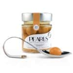 Frasco de esferificaciones de gazpacho Pearls con la cucharilla de servicio y una Pearl, sobre fondo blanco
