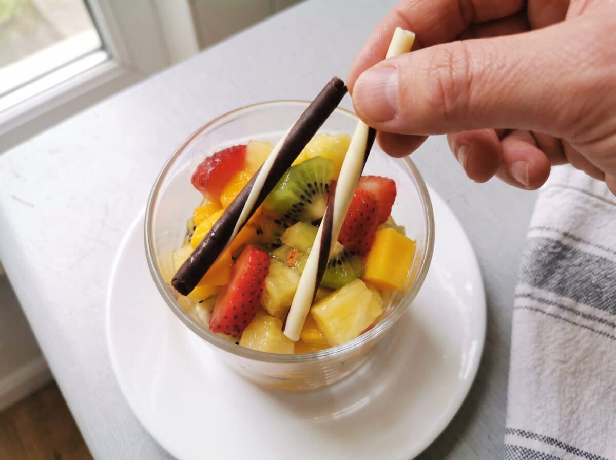 Cruzando dos barquillos de chocolate sobre la fruta de la copita