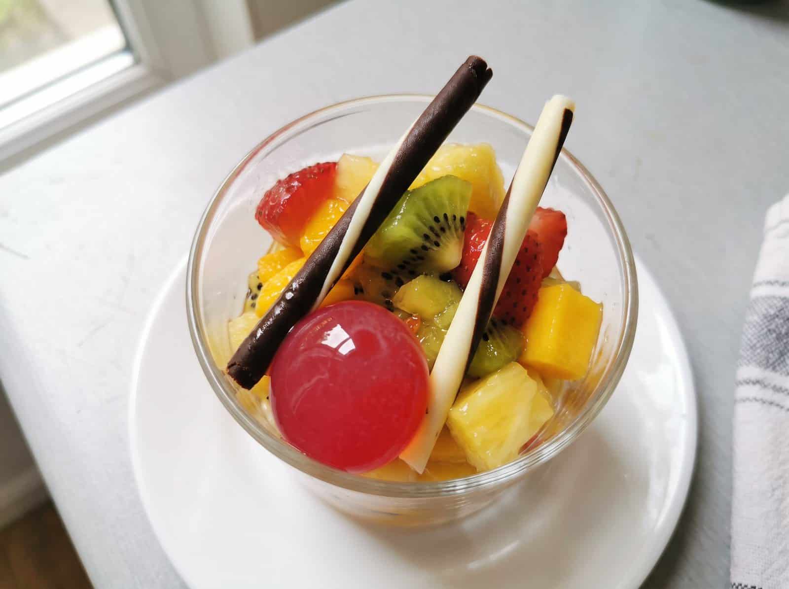 Copita de cristal con macedonia de kiwi, fresa, mango y piña, dos barquillos de chocolate y una Pearl de Frambuesa encima