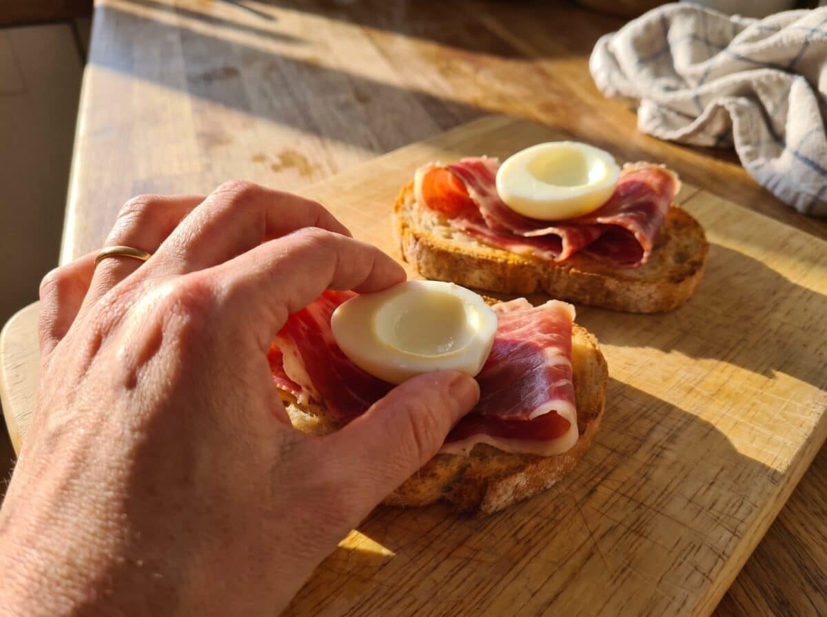 Colocando medio huevo de codorniz sobre el jamón de la tosta