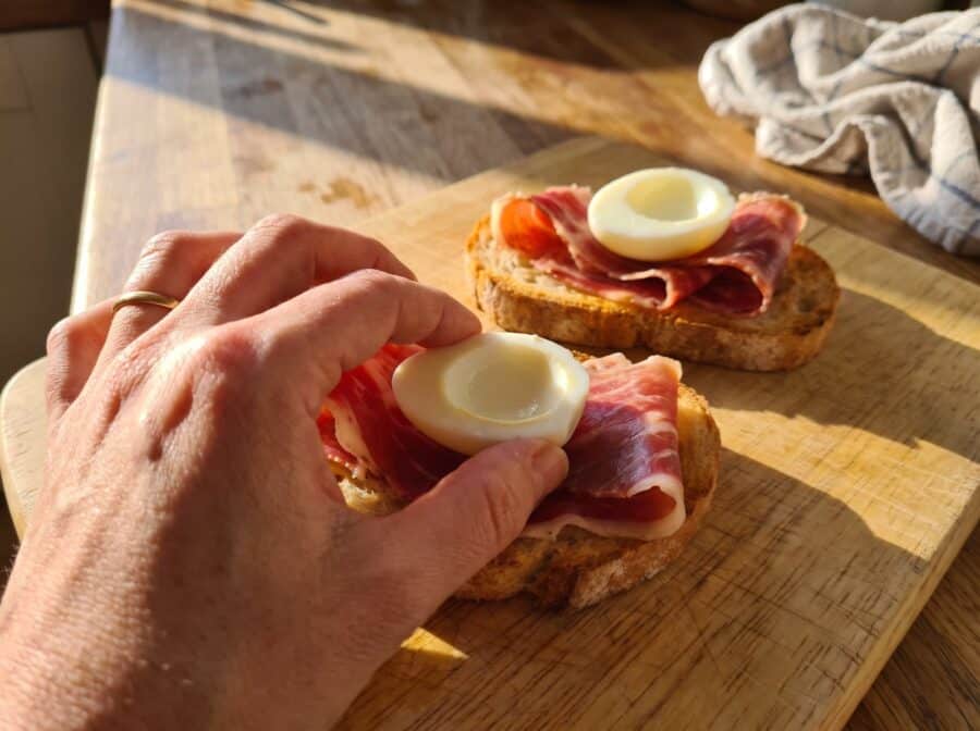 Colocando medio huevo de codorniz sobre el jamón de la tosta